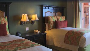 Quarto de hotel com duas camas, uma mesa de cabeceira com telefone e luminárias fixadas na parede.