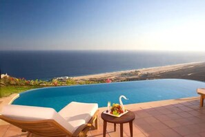 A poolside area with a view of the ocean and a table with a fruit arrangement. - Montecristo Villa with Oceanviews (Cabo San Lucas)