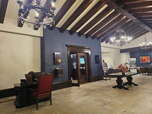 A lobby with a reception desk, a red upholstered chair, a wooden table with a vase of flowers, and a chandelier. - Montecristo Villa with Oceanviews (Cabo San Lucas)