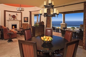 A dining area with a round table, chairs, a fruit bowl, and a view of the ocean. - Montecristo Villa with Oceanviews (Cabo San Lucas)