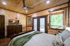 A wooden cabin bedroom with a bed, dresser, and a painting on the wall. - The whole family will love The Rusty Rose Retreat (Broken Bow)