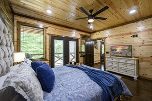 Een slaapkamer met een bed, een kaptafel, een plafondventilator en een televisie.