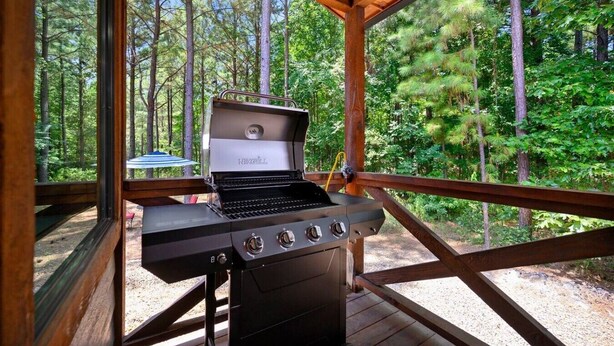 Een draagbare grill met een laptop op een houten terras, omringd door een bos.