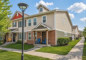 A two-story residential building with a front porch, a street lamp, and a well-maintained lawn.