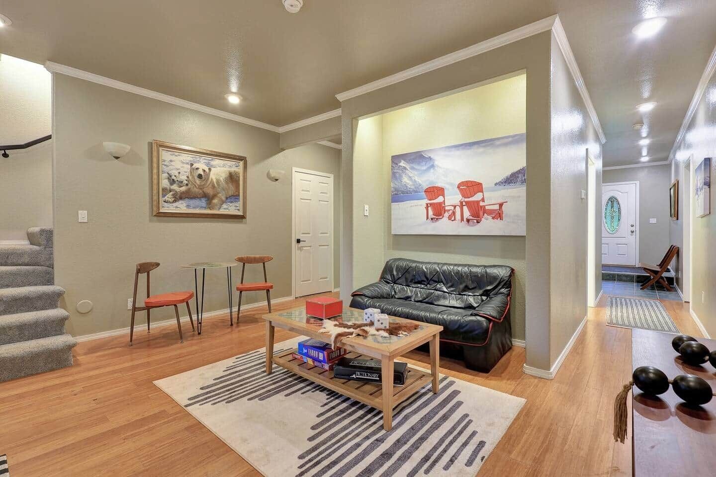 A living room with a sofa, chairs, a coffee table, and a painting on the wall.