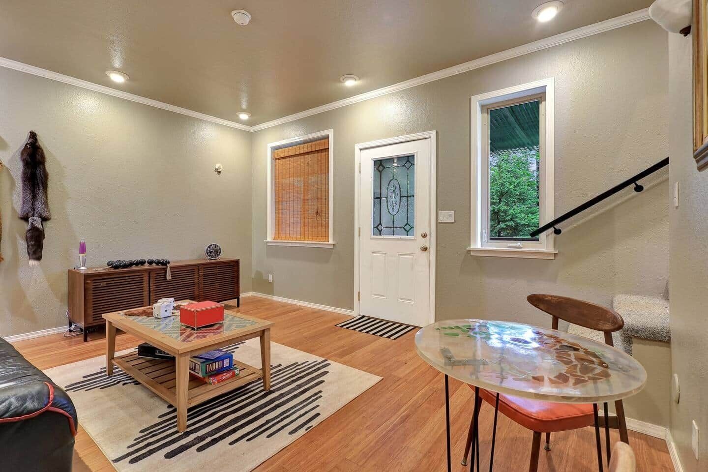 Una sala de estar con chimenea, una mesa de centro de vidrio, un sofá y una escalera.