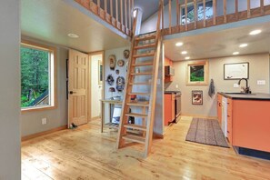 Un interior de varios niveles con una escalera de madera, una zona de cocina y un comedor.
