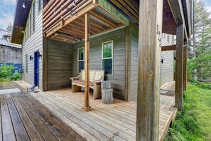 Una terraza de madera con un banco y un porche cubierto.