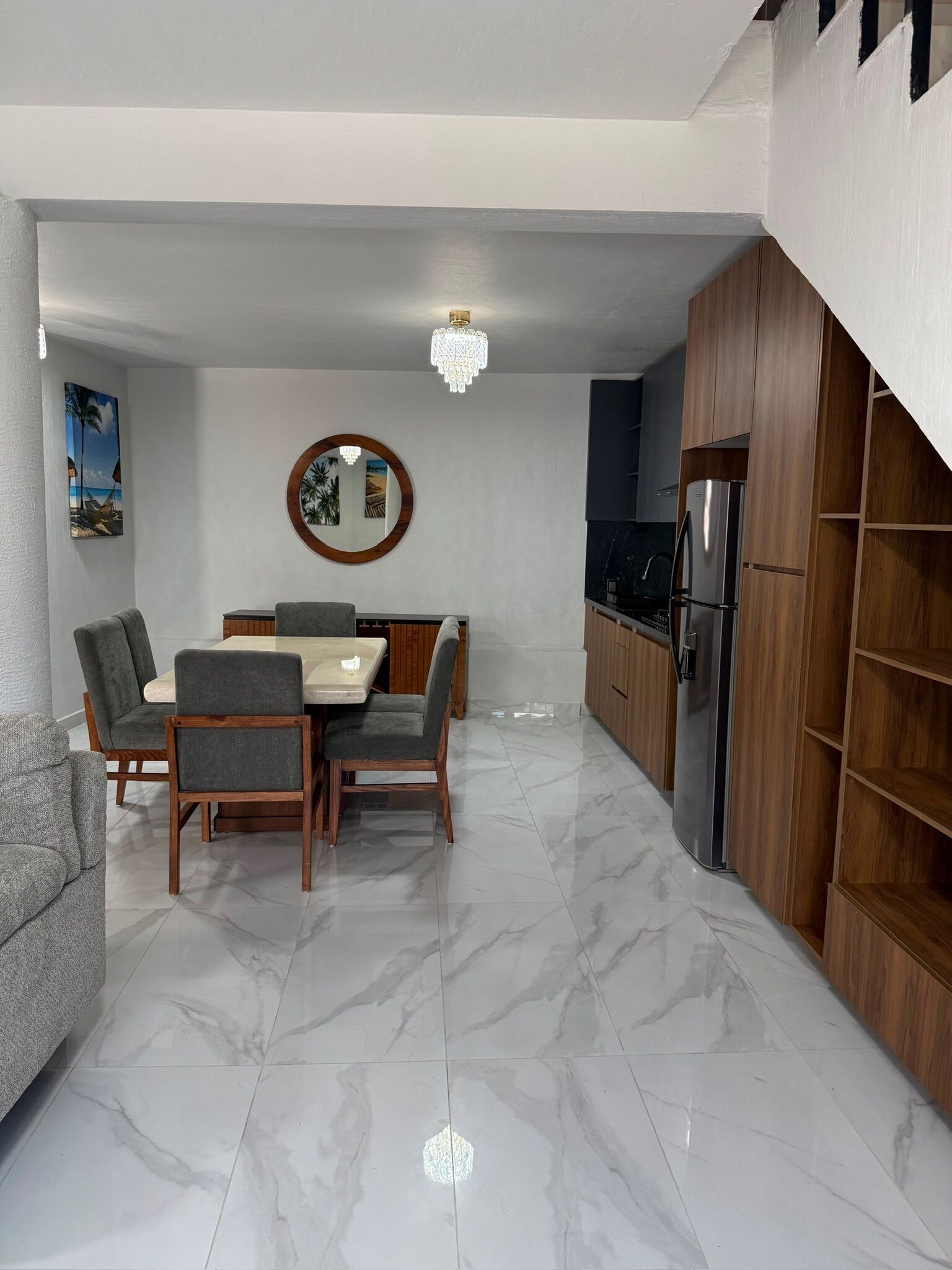 Una cocina moderna con piso de mármol, gabinetes de madera y un comedor con mesa y sillas.