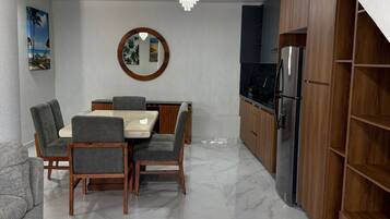 Una cocina moderna con piso de mármol, gabinetes de madera y un comedor con mesa y sillas.