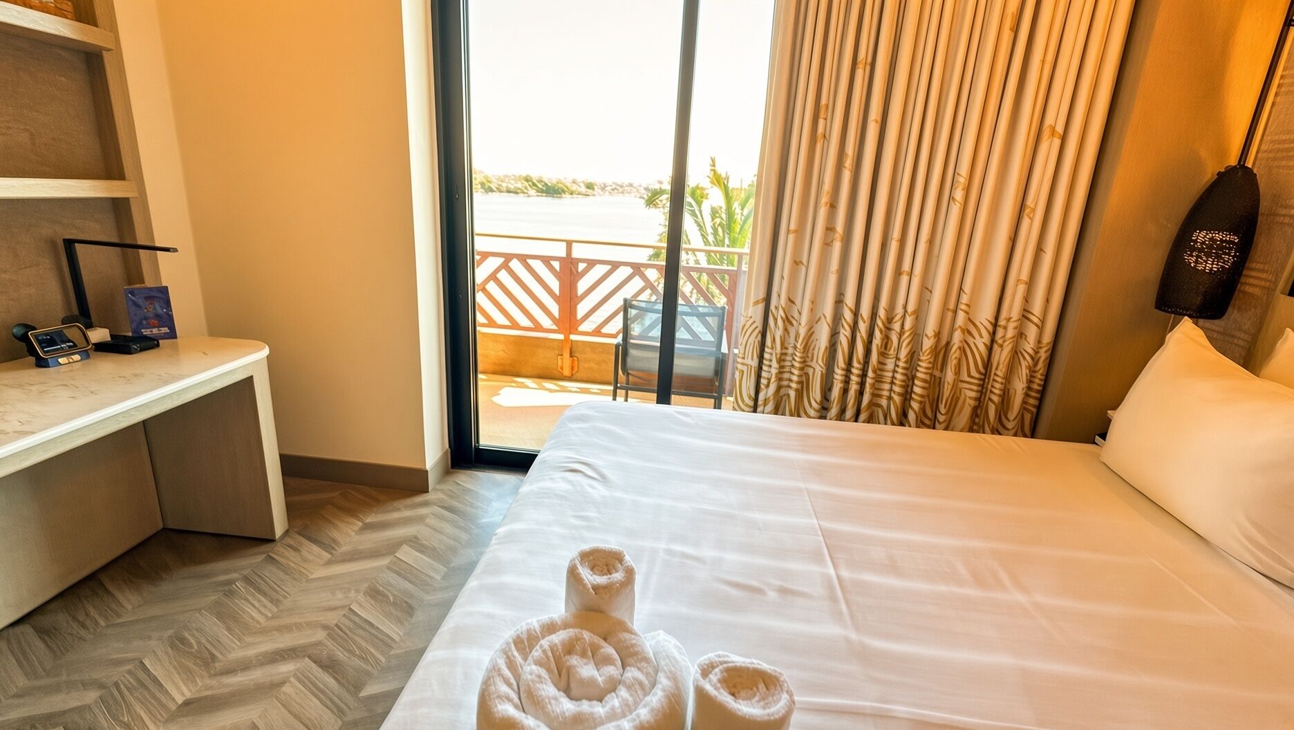 A hotel room with a bed, a desk, and a view of the outdoors.