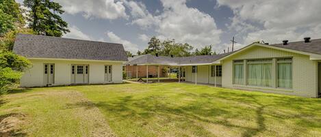 A residential property with a grassy yard, a brick house, and a covered porch.