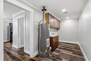 A modern kitchen with wooden cabinets, a stainless steel water heater, and a white countertop. - Awesome 4-bedroom house with AC in charming Monroe (Monroe)