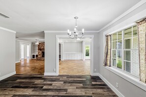 A spacious interior with a wooden floor, a chandelier, and a large window with curtains. - Awesome 4-bedroom house with AC in charming Monroe (Monroe)