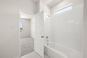 A bathroom with white tiled walls, a bathtub, and a shower. - Luxurious 6-bedroom house near UNT & Medical City (Denton)