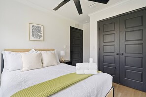 Ein Hotelzimmer mit einem Bett, einer Nachttischlampe, einem gerahmten Motivationszitat und mehreren dunkel gefärbten Türen.