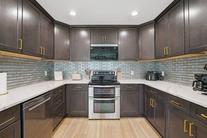 A modern kitchen with dark wood cabinets, a stainless steel oven, and a tiled backsplash.