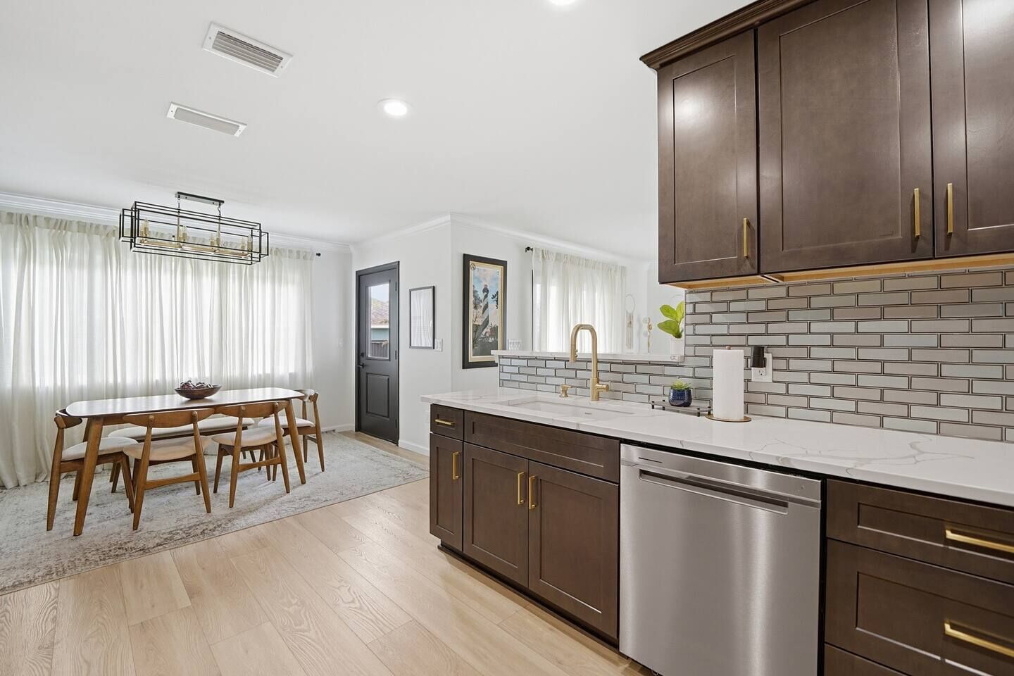 A modern kitchen with a white countertop, stainless steel appliances, and dark wooden cabinets.