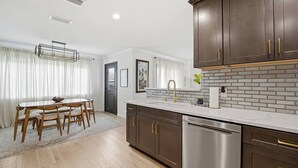 Una cocina moderna con encimera blanca, electrodomésticos de acero inoxidable y armarios de madera oscura.