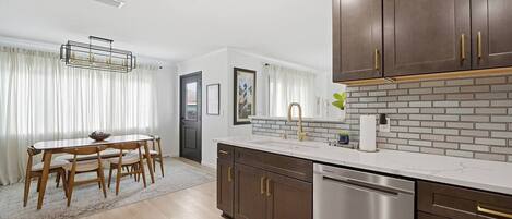 A modern kitchen with a white countertop, stainless steel appliances, and dark wooden cabinets.