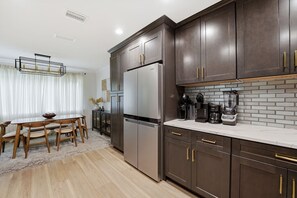 A modern kitchen with dark cabinetry, a stainless steel refrigerator, and a coffee maker on the counter.
