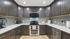 A modern kitchen with dark cabinetry, a stainless steel oven, and a microwave.