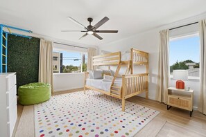 A room with a bunk bed, a ceiling fan, a green bean bag, a polka dot rug, and a window with curtains. - Anastasia Island Retreat - Villa A - Walk Downtown (St. Augustine)