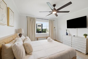 Ein Hotelzimmer mit einem Bett, einem Schreibtisch, einem Fernseher und einem Deckenventilator.