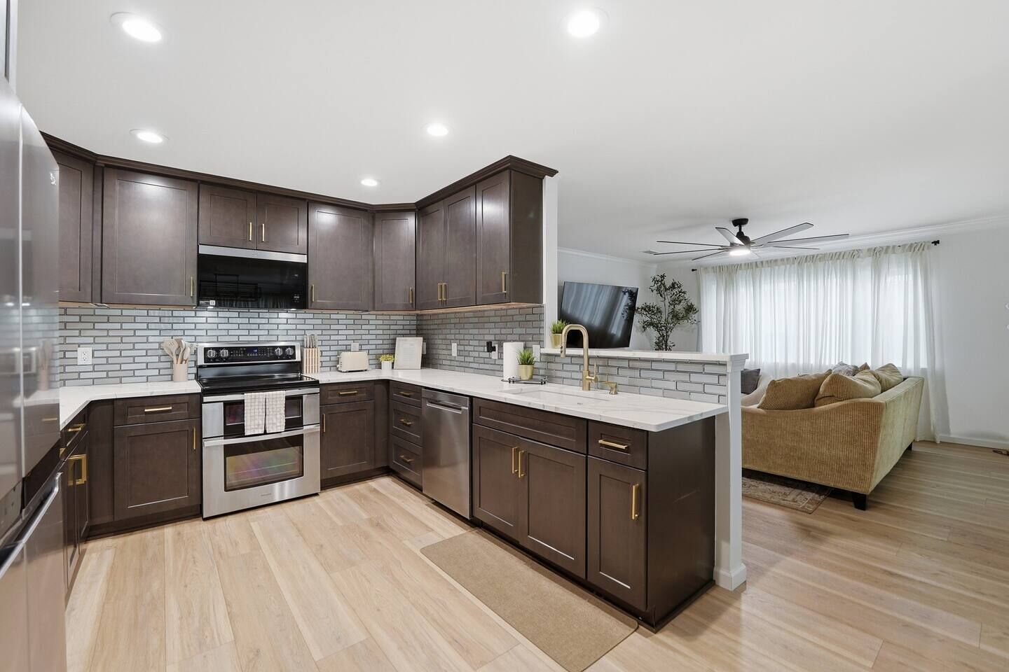 Une cuisine moderne avec des meubles de couleur sombre, une cuisinière en acier inoxydable et un four encastré.