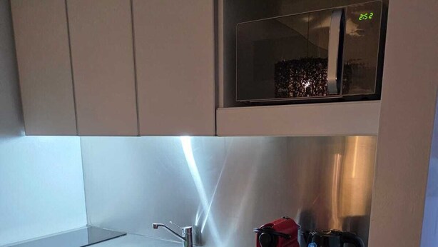 A compact kitchen with a stainless steel sink, a microwave, and a coffee maker on the countertop.