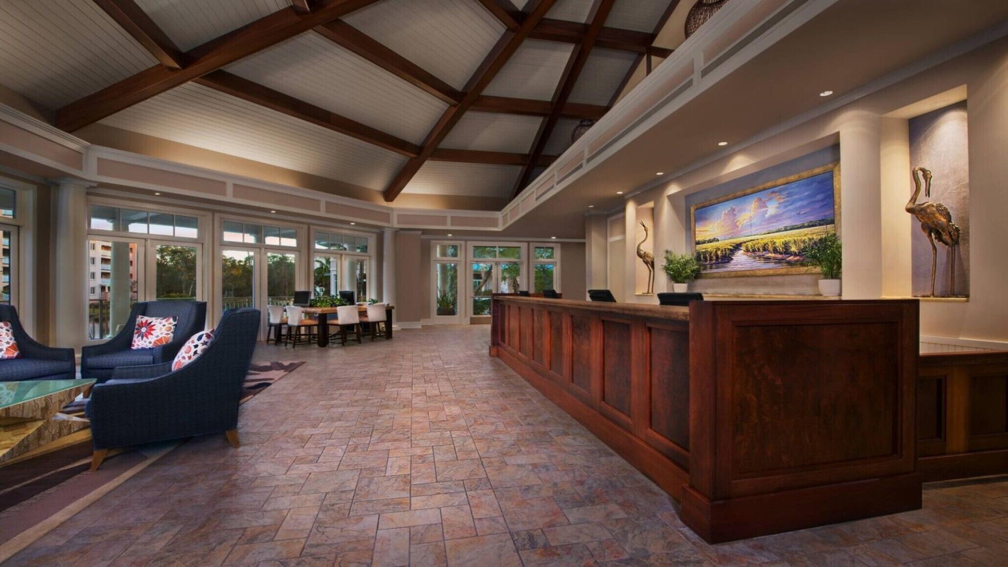 Eine geräumige Lobby mit hoher Decke, einem Empfangsbereich, bequemen Sitzgelegenheiten und großen Fenstern mit Blick ins Freie.