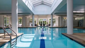 A large indoor swimming pool with clear blue water, surrounded by white columns and large windows allowing natural light. - Coastal SurfWatch Getaway with Ocean Vista & Spacious 2BR Comfort (Hilton Head Island)