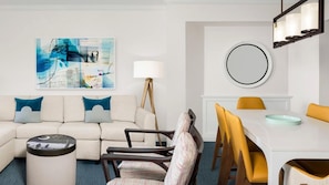 A modern living room with a sofa, chairs, a dining table, and a painting. - Coastal SurfWatch Getaway with Ocean Vista & Spacious 2BR Comfort (Hilton Head Island)