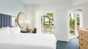 A hotel room with a large bed, a bedside table with a lamp, a chair, a wooden dresser, and a balcony with a view of trees. - Coastal SurfWatch Getaway with Ocean Vista & Spacious 2BR Comfort (Hilton Head Island)