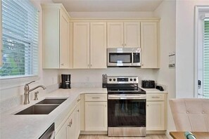 A kitchen with white cabinets, a stainless steel microwave, and an oven. - Margaritaville 4BR | Sleeps 10 | Near Disney (Kissimmee)