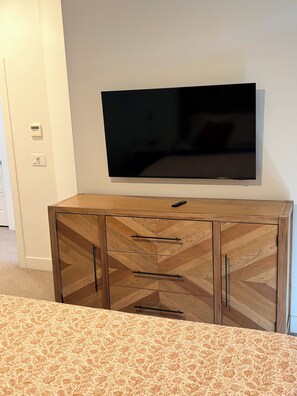 A wooden cabinet with drawers and a flat-screen TV mounted on the wall.