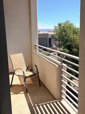A balcony with a single chair, a white railing, and a view of a building and trees. - The Desert Belle, No. 1 Loft at The Lofts,  4BR 3.5BA Southern Utah Retreat (Saint George)