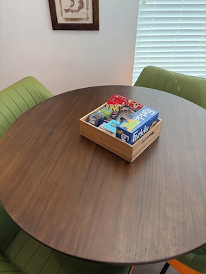 A round wooden table with a box of board games in the center. - The Desert Belle, No. 1 Loft at The Lofts,  4BR 3.5BA Southern Utah Retreat (Saint George)