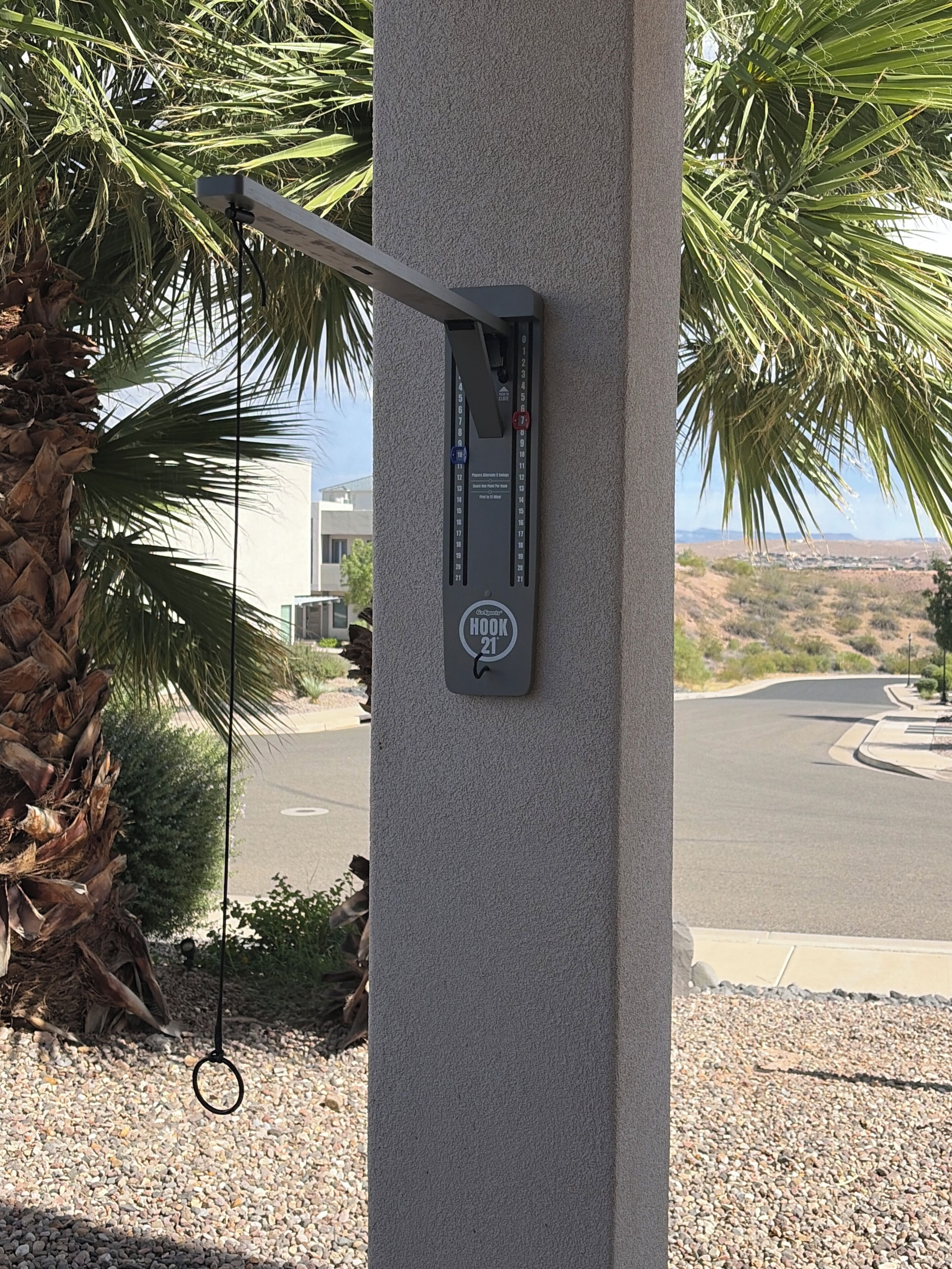 A security hook attached to a concrete pillar with a view of a road and desert landscape in the background.