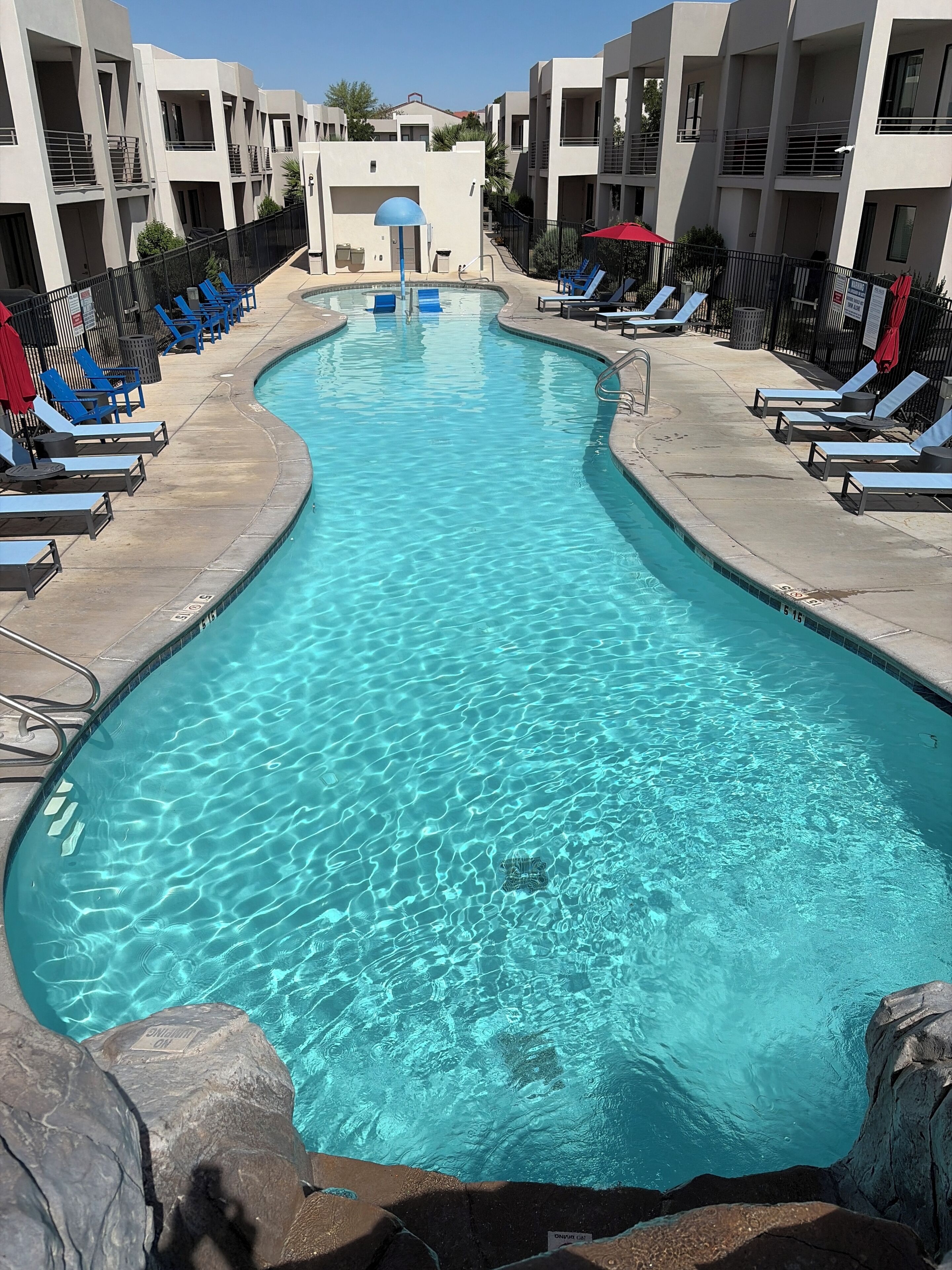 A swimming pool with lounge chairs and a modern building in the background.