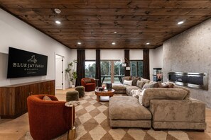 Un salon moderne doté d’un grand téléviseur à écran plat, de si èges confortables et offrant une vue sur l’extérieur.