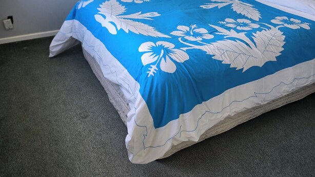 Ein Schlafzimmer mit einem Bett, einer weißen Wand und einem Teppichboden.