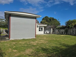 A residential backyard with a garage, a small patio with outdoor furniture, and a wooden fence. - Middleton Near The Beach (Paraparaumu Beach)