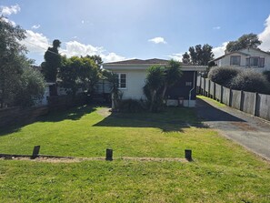 A residential property with a fenced yard, a pathway leading to a house, and a neighboring building. - Middleton Near The Beach (Paraparaumu Beach)