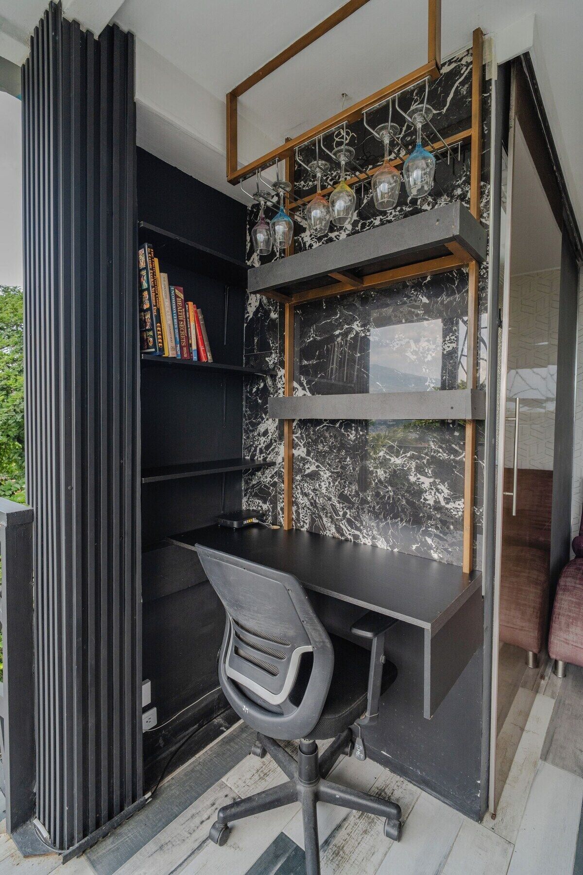 Un espacio de oficina moderno con un escritorio negro, una silla y una estantería llena de libros.