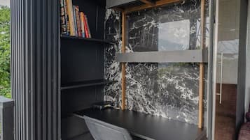 Un espacio de oficina moderno con un escritorio negro, una silla y una estantería llena de libros.