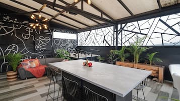 Un interior moderno con una zona de bar central, asientos y un diseño de pared geométrico.
