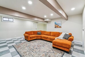 A living room with a sectional sofa, a patterned rug, and a painting on the wall.