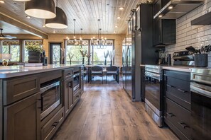 Eine moderne Küche mit Holzboden, Edelstahlgeräten und Pendelleuchten.