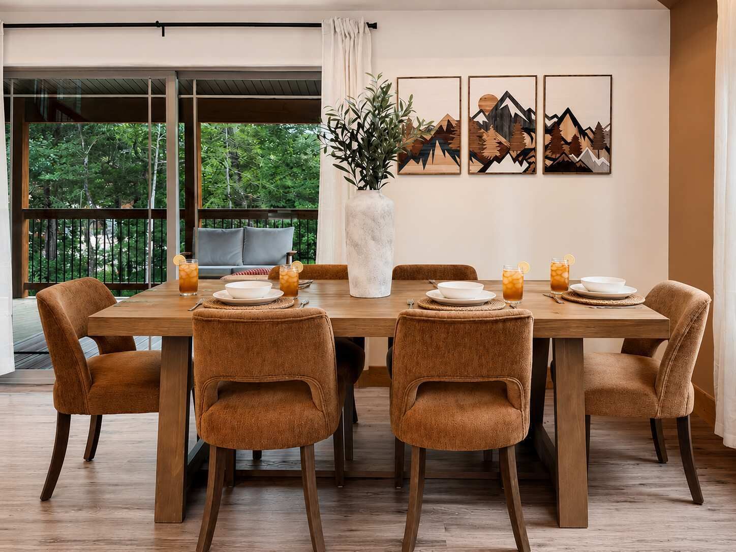 Un coin repas avec une table en bois, six chaises et un vase agrémenté de plantes vertes.